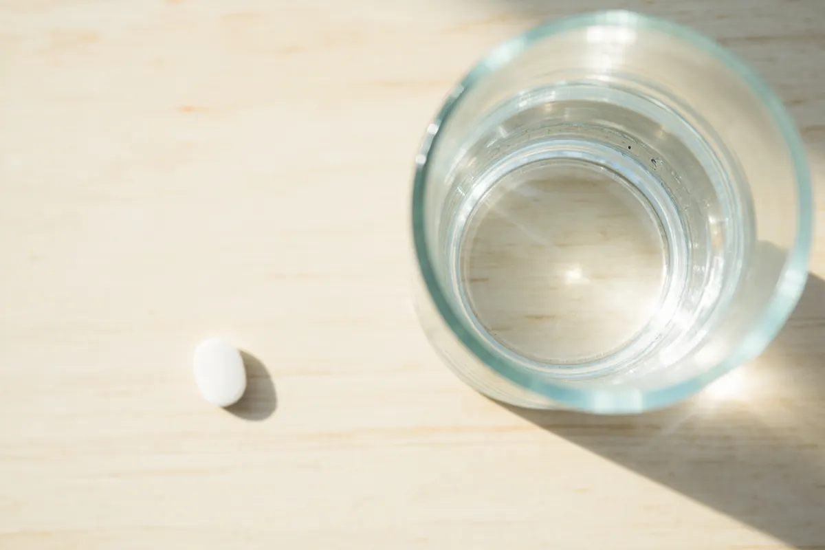 Cápsula blanca de uso farmacéutico sobre superficie neutra
