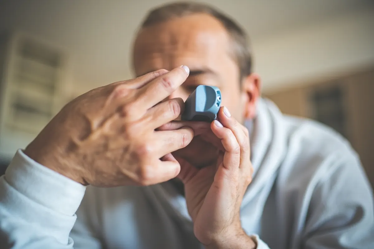Persona adulta usando correctamente un inhalador para el asma