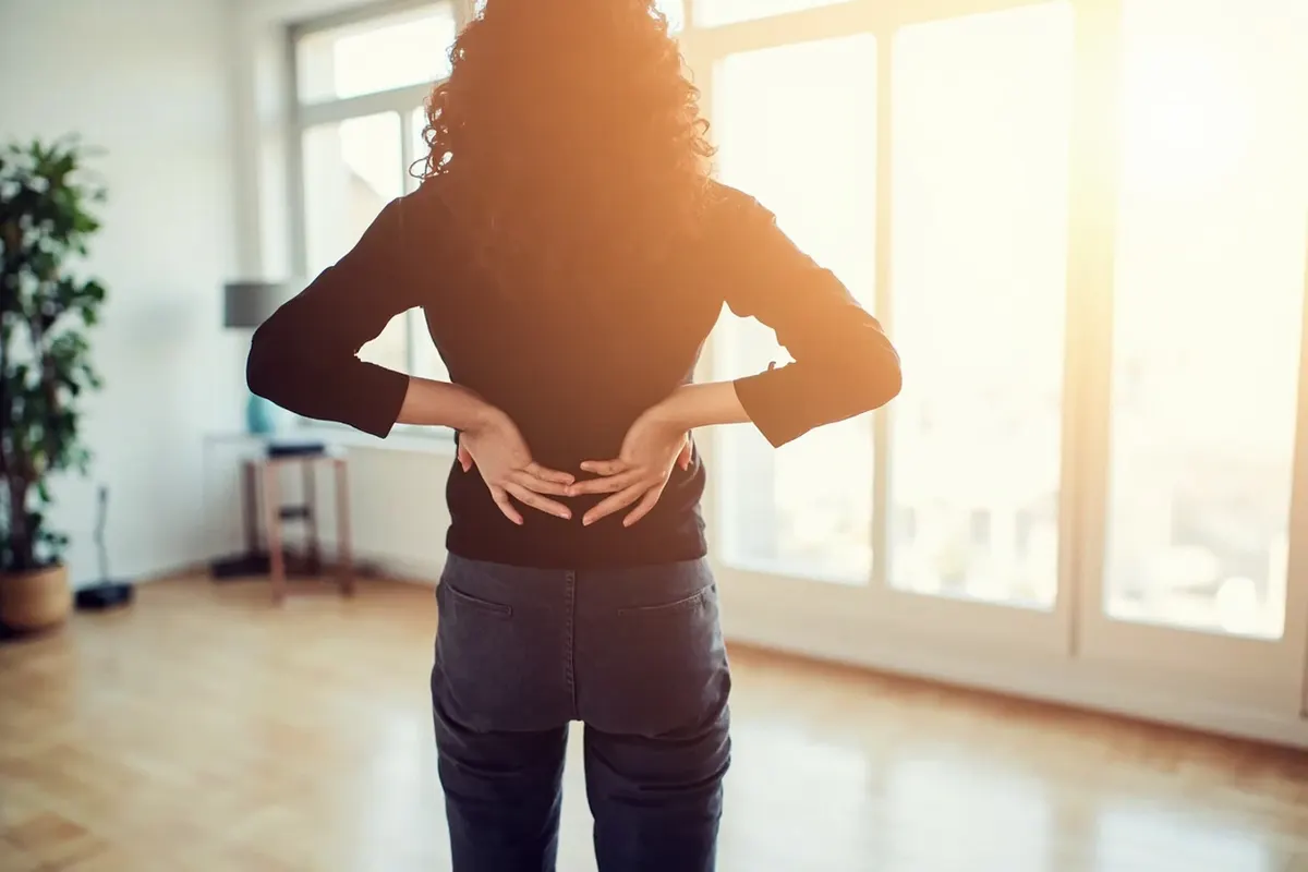 Persona estirando suavemente la zona lumbar en casa