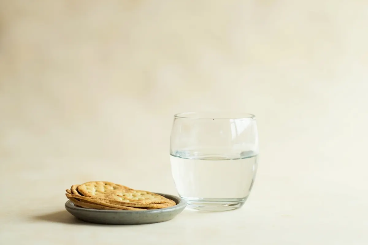 Vaso de agua con galletas saladas, medidas suaves para aliviar las náuseas