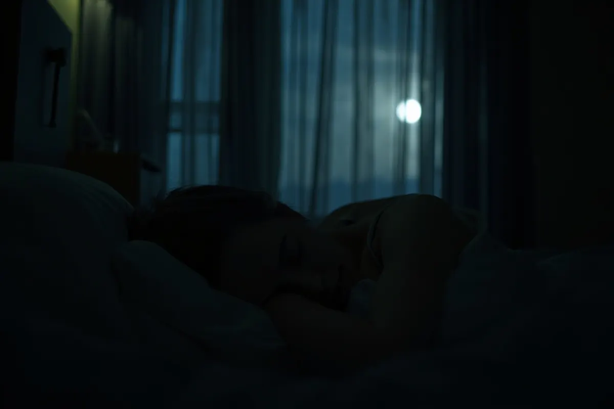 Mujer joven durmiendo en un dormitorio oscuro